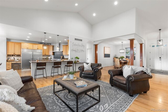 5653 Yank St, Arvada, CO 80002 - living area featuring decorative columns, arched walkways, light wood finished floors, high vaulted ceiling, and recessed lighting