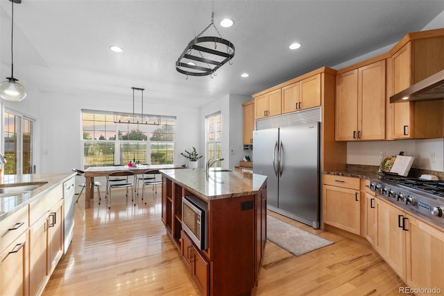 5653 Yank St, Arvada, CO 80002 - kitchen with built in appliances, recessed lighting, dark stone countertops, light brown cabinets, and light wood finished floors