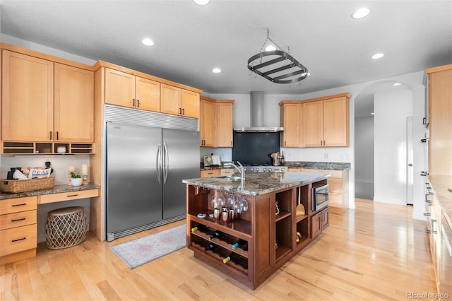 5653 Yank St, Arvada, CO 80002 - kitchen featuring built in appliances, wall chimney range hood, open shelves, light brown cabinets, and arched walkways
