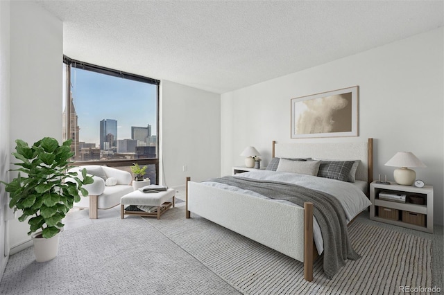 bedroom with floor to ceiling windows, carpet floors, and a textured ceiling