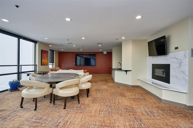 dining room featuring floor to ceiling windows, sink, light colored carpet, and a fireplace