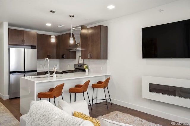 kitchen with appliances with stainless steel finishes, decorative light fixtures, sink, dark brown cabinetry, and kitchen peninsula