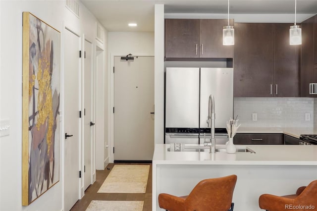 kitchen with a breakfast bar, dark brown cabinets, stainless steel refrigerator, and decorative light fixtures