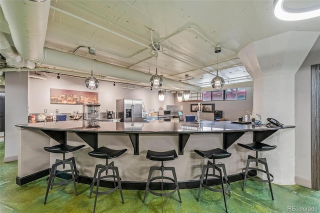 kitchen featuring decorative light fixtures, concrete flooring, and stainless steel fridge with ice dispenser