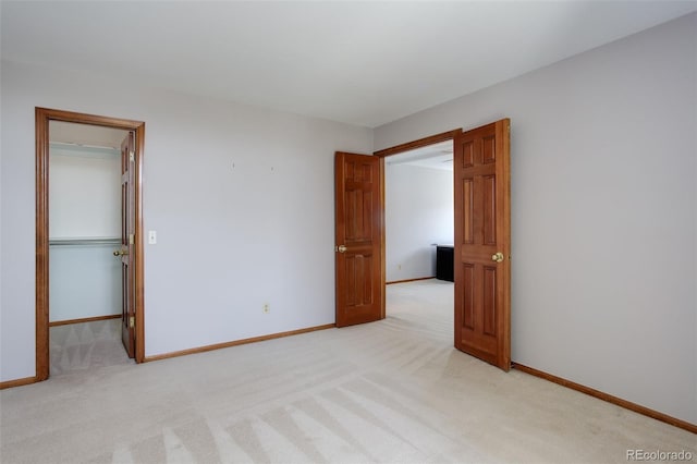 3951 S Carson St Unit D, Aurora, CO 80014 - unfurnished bedroom featuring light carpet, a walk in closet, baseboards, and a closet