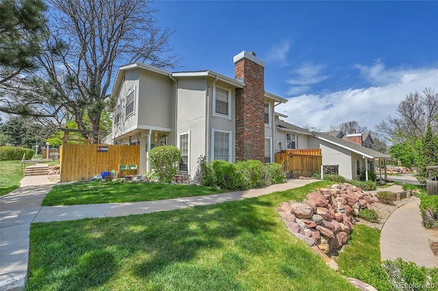 view of side of home with a lawn, fence, and a chimney