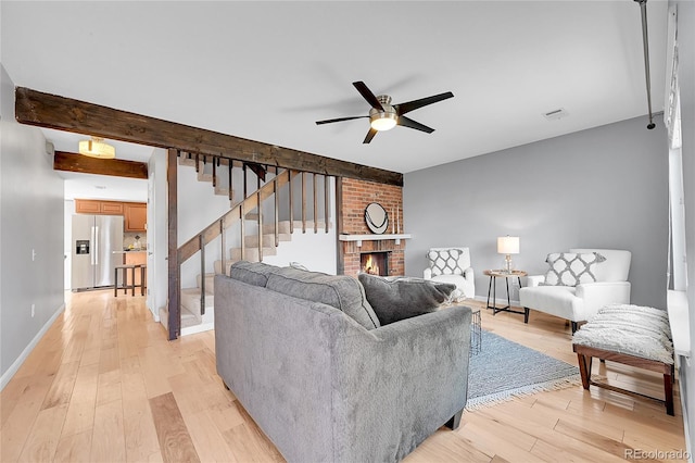 living room with ceiling fan, a fireplace, light wood-style floors, visible vents, and stairway