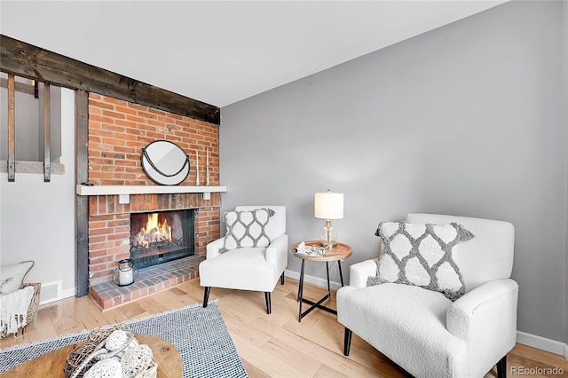 sitting room featuring baseboards, wood finished floors, visible vents, and a fireplace
