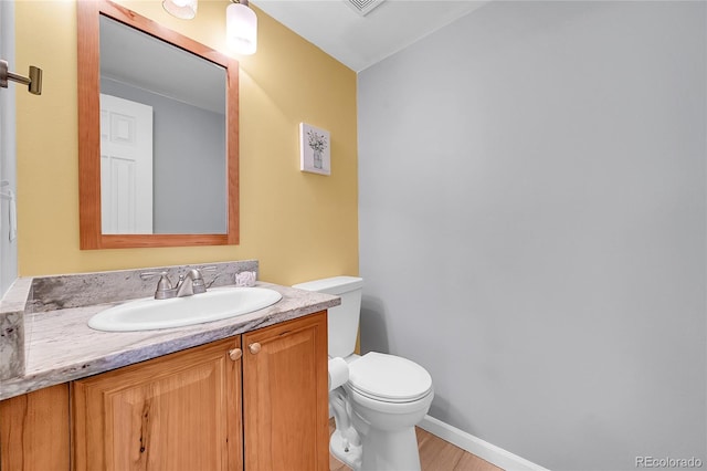bathroom featuring vanity, baseboards, wood finished floors, and toilet