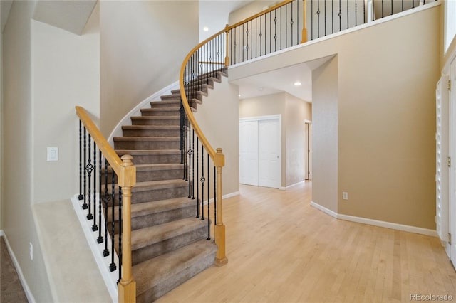 staircase with a high ceiling and hardwood / wood-style floors