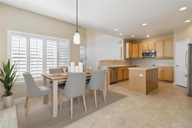 kitchen with decorative light fixtures, stainless steel appliances, a center island, sink, and light brown cabinets