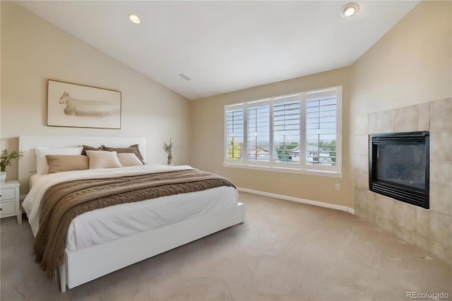 carpeted bedroom featuring lofted ceiling and a tile fireplace