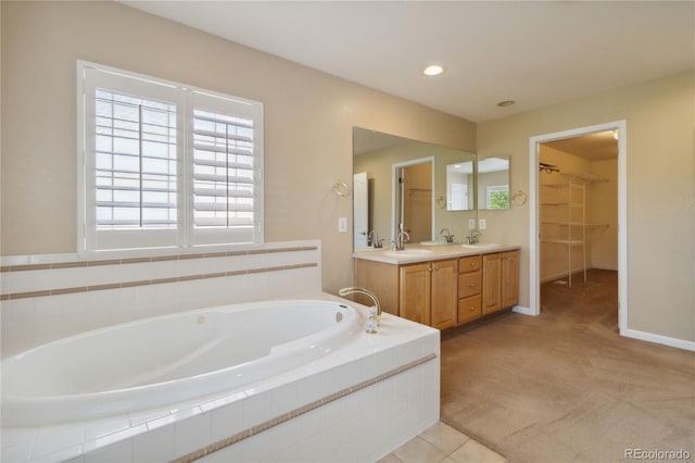 bathroom featuring a relaxing tiled tub and vanity