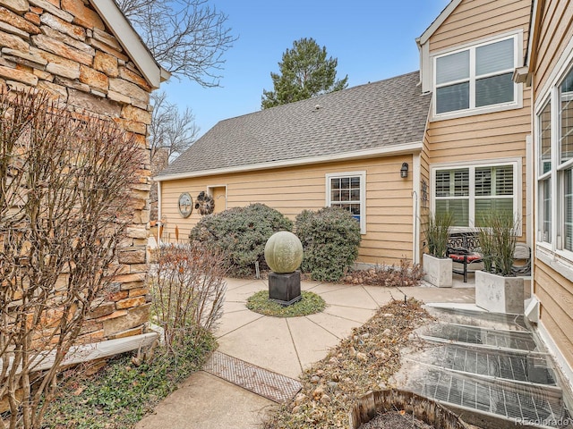 exterior space with a patio and roof with shingles