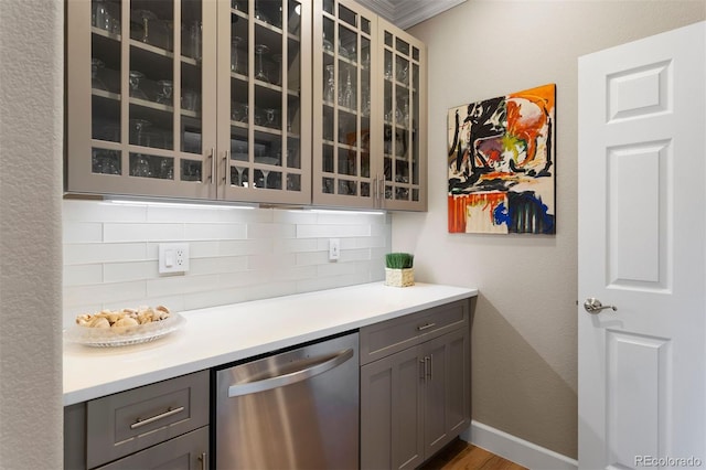 kitchen with hardwood / wood-style floors, dishwasher, backsplash, gray cabinets, and ornamental molding