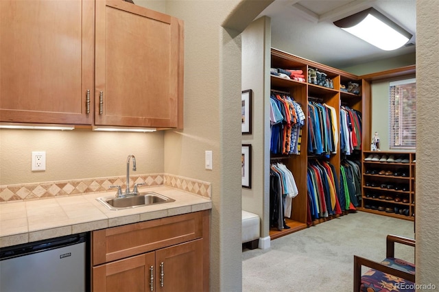 interior space with dishwasher, sink, light colored carpet, and tile counters