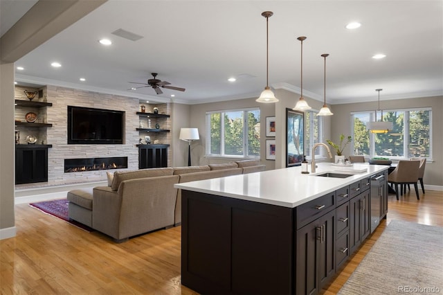 kitchen with decorative light fixtures, light hardwood / wood-style flooring, ceiling fan, and sink