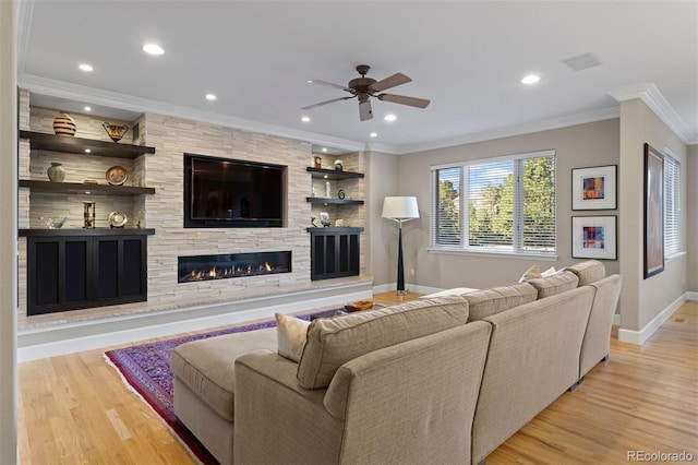 living room featuring a fireplace, light hardwood / wood-style floors, ceiling fan, and crown molding