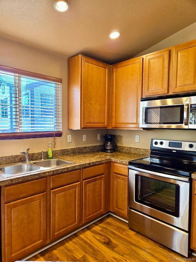 kitchen with recessed lighting, appliances with stainless steel finishes, dark wood-type flooring, a sink, and a textured ceiling