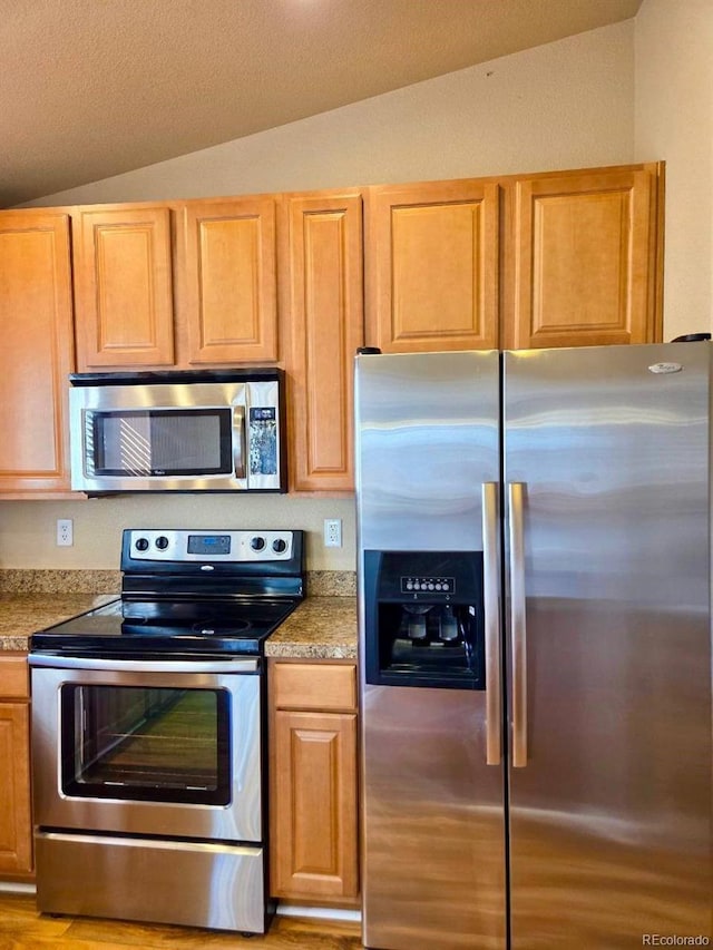 kitchen featuring appliances with stainless steel finishes and lofted ceiling