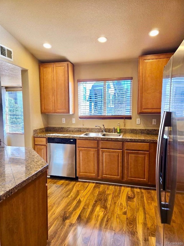 kitchen featuring stainless steel appliances, visible vents, a sink, and dark wood-type flooring