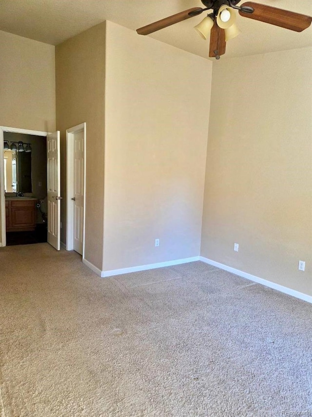 spare room with baseboards, ceiling fan, a towering ceiling, and light colored carpet