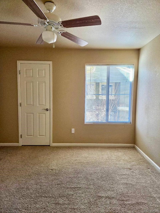 unfurnished room featuring carpet flooring, ceiling fan, a textured ceiling, and baseboards