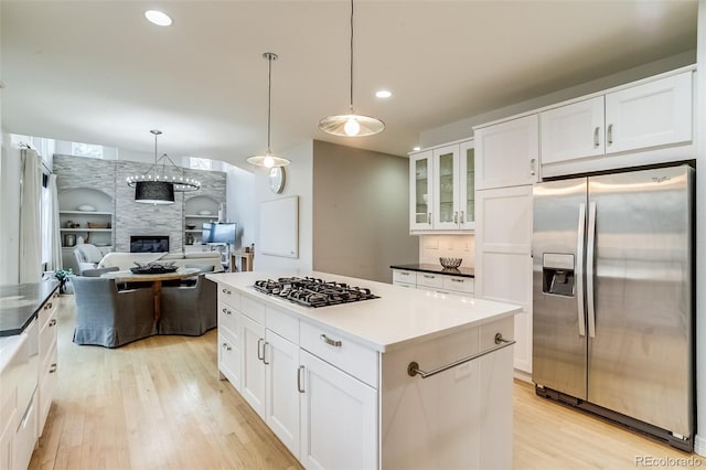 2464 Ginny Way, Lafayette, CO 80026 - kitchen with stainless steel appliances, light wood-type flooring, a large fireplace, white cabinetry, and glass insert cabinets