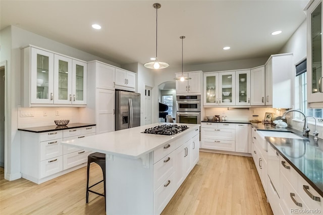 2464 Ginny Way, Lafayette, CO 80026 - kitchen with stainless steel appliances, a sink, decorative backsplash, a center island, and light wood-style flooring