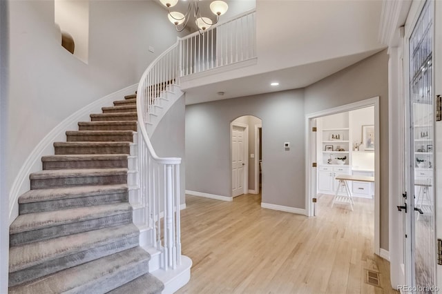 2464 Ginny Way, Lafayette, CO 80026 - stairs with arched walkways, wood finished floors, a towering ceiling, baseboards, and a chandelier