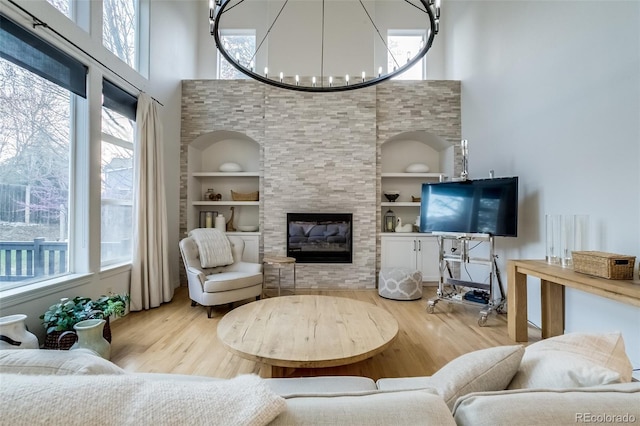 2464 Ginny Way, Lafayette, CO 80026 - living area featuring wood finished floors, built in shelves, a chandelier, plenty of natural light, and a towering ceiling
