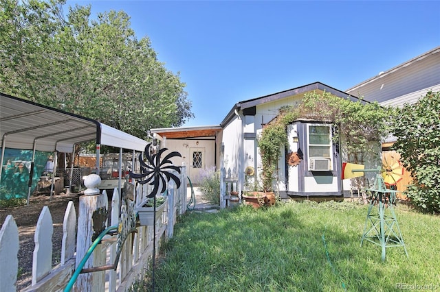 view of front of house with cooling unit, a carport, an outdoor structure, and a front yard