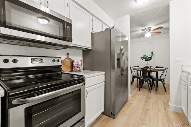 kitchen with white cabinetry, a textured ceiling, light wood-type flooring, ceiling fan, and stainless steel appliances