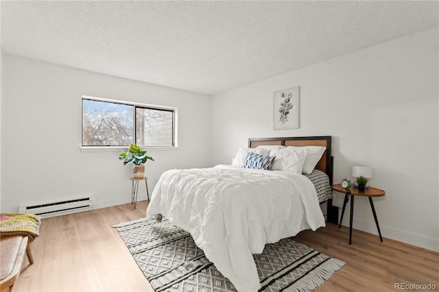 bedroom featuring baseboard heating, wood-type flooring, and a textured ceiling