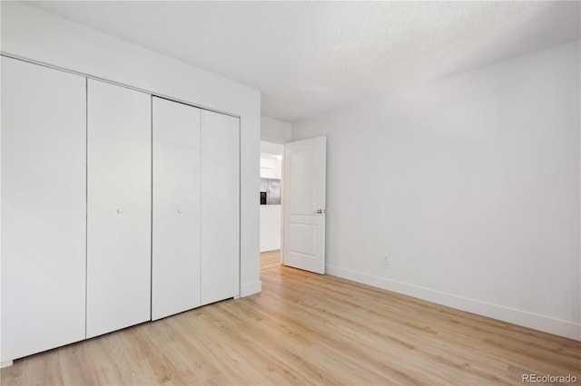 unfurnished bedroom featuring a closet, light hardwood / wood-style flooring, and a textured ceiling