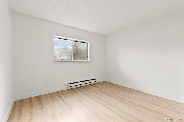 empty room featuring a baseboard radiator, light hardwood / wood-style flooring, and a textured ceiling