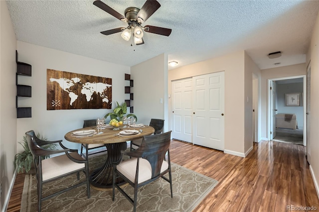 dining area with hardwood / wood-style floors, a textured ceiling, and ceiling fan