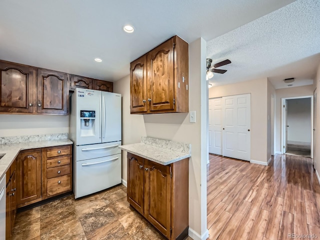 kitchen with light stone countertops, a textured ceiling, white appliances, ceiling fan, and hardwood / wood-style flooring