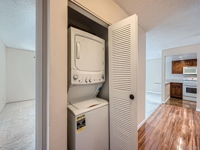 laundry area featuring hardwood / wood-style floors, stacked washer / drying machine, and a textured ceiling