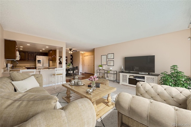 living area featuring light colored carpet, baseboards, a ceiling fan, and recessed lighting