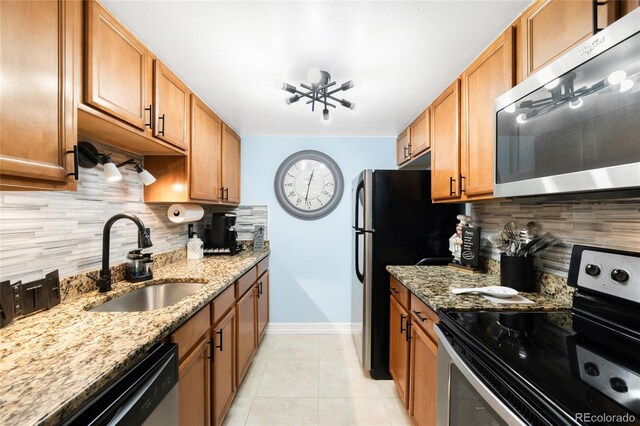 7780 W 38th Ave Unit 203, Wheat Ridge, CO 80033 - kitchen with appliances with stainless steel finishes, a sink, baseboards, backsplash, and light stone counters