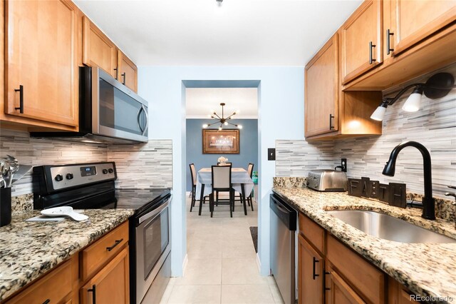 7780 W 38th Ave Unit 203, Wheat Ridge, CO 80033 - kitchen with appliances with stainless steel finishes, a sink, decorative backsplash, light tile patterned flooring, and light stone counters