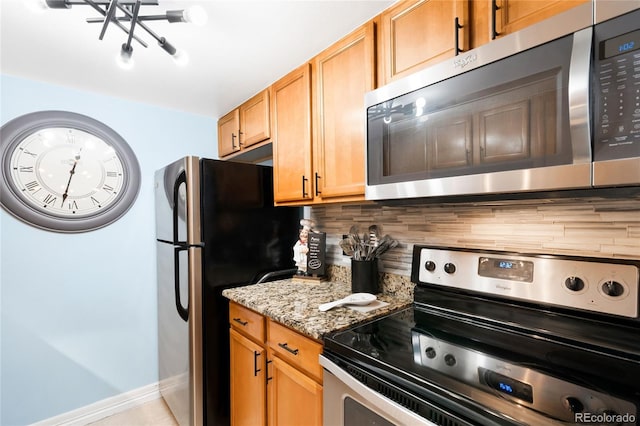 7780 W 38th Ave Unit 203, Wheat Ridge, CO 80033 - kitchen featuring appliances with stainless steel finishes, backsplash, light stone countertops, and baseboards