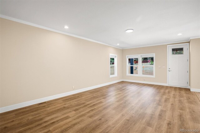 unfurnished room with ornamental molding and light wood-type flooring