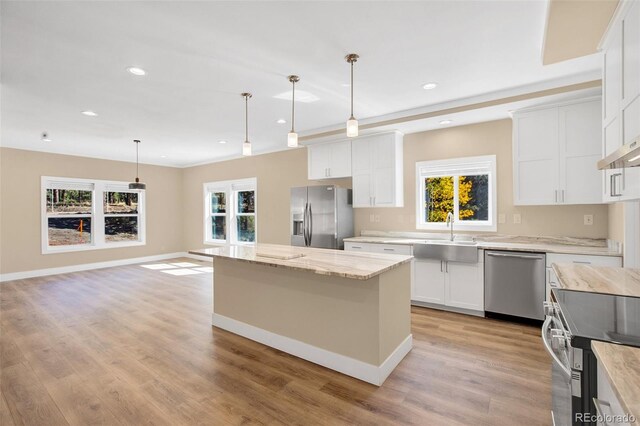 kitchen featuring white cabinets, decorative light fixtures, appliances with stainless steel finishes, and a healthy amount of sunlight