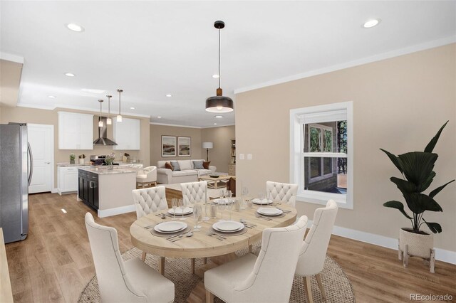 dining space featuring light wood-type flooring and ornamental molding