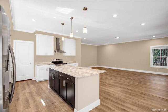 kitchen with light hardwood / wood-style floors, light stone counters, stainless steel appliances, decorative light fixtures, and wall chimney range hood