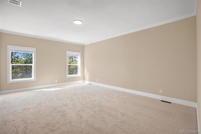 empty room featuring light colored carpet and crown molding