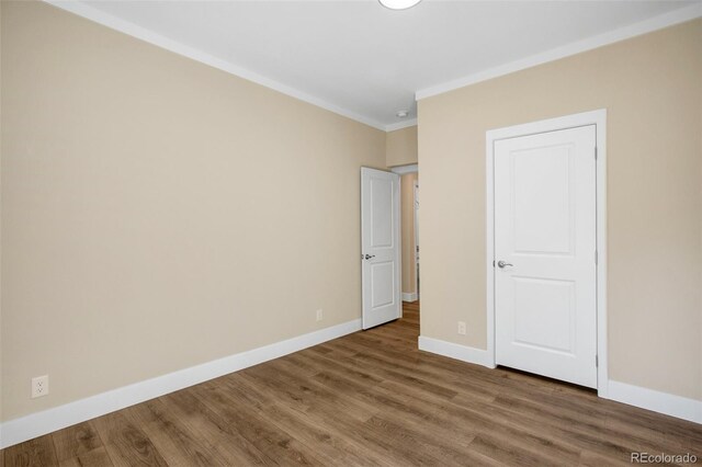 unfurnished bedroom featuring wood-type flooring and crown molding