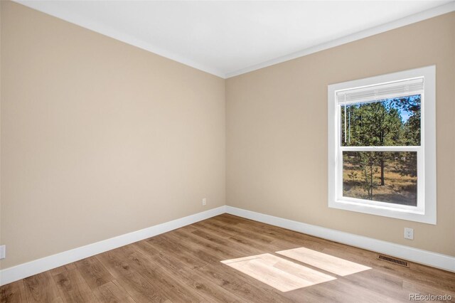 empty room with light wood-type flooring and crown molding